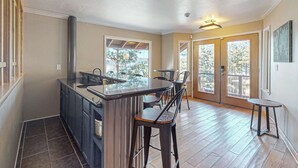 A kitchen with a central island, bar stools, and a view through large windows. - Luxury home with game room, sauna, and stunning lake views (Zephyr Cove)