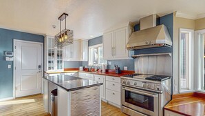 A modern kitchen with a central island, stainless steel appliances, and a built-in range hood. - Luxury home with game room, sauna, and stunning lake views (Zephyr Cove)