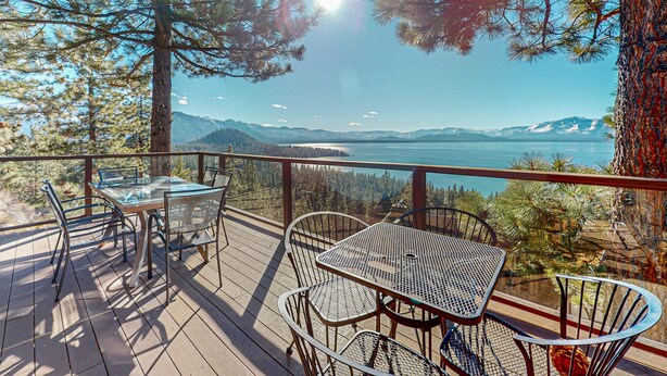 A deck with metal furniture overlooking a lake and mountains. - Luxury home with game room, sauna, and stunning lake views (Zephyr Cove)