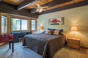 A bedroom with a bed, two bedside tables, a desk, a foosball table, and a ceiling fan.