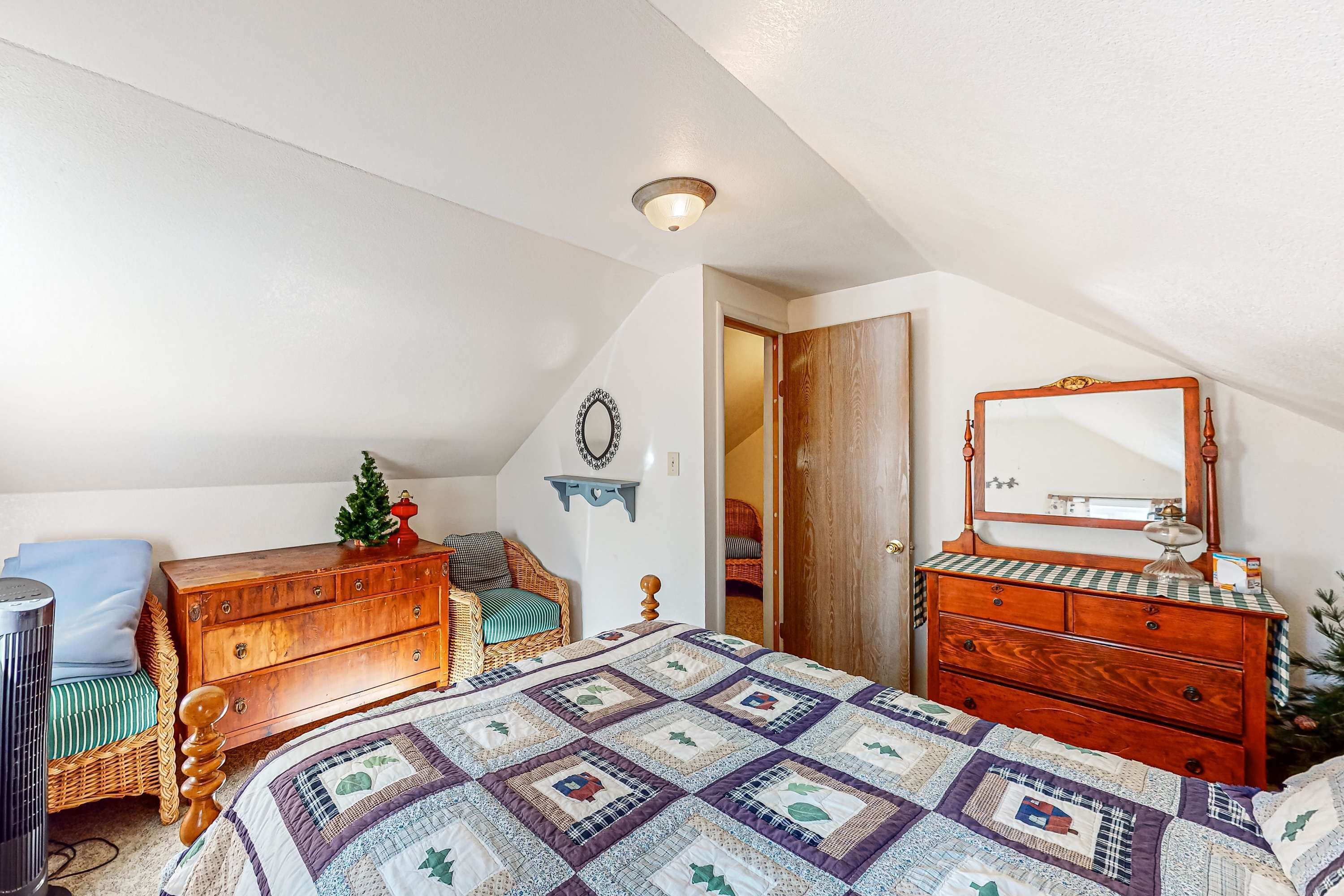 Un dormitorio con cama, cómoda, silla y espejo.