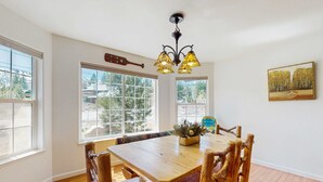 Un coin repas avec une table et des chaises en bois, un luminaire suspendu et un tableau au mur.