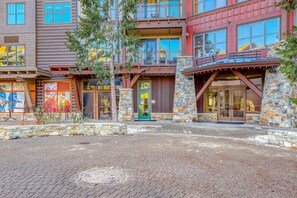 A multi-story building with a stone facade, a green door, and a balcony with railings. - Ideal Mountain Getaway Near the Lifts with Private Balcony, Free WiFi & Fireplace (NorthStar-Truckee)