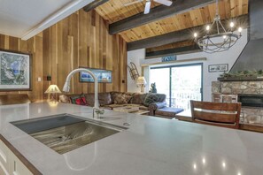 Une cuisine dotée d’un îlot central, d’une cheminée en pierre et d’un plafond en bois.