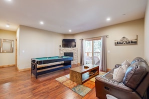 A living room with a pool table, a sofa, and a fireplace.