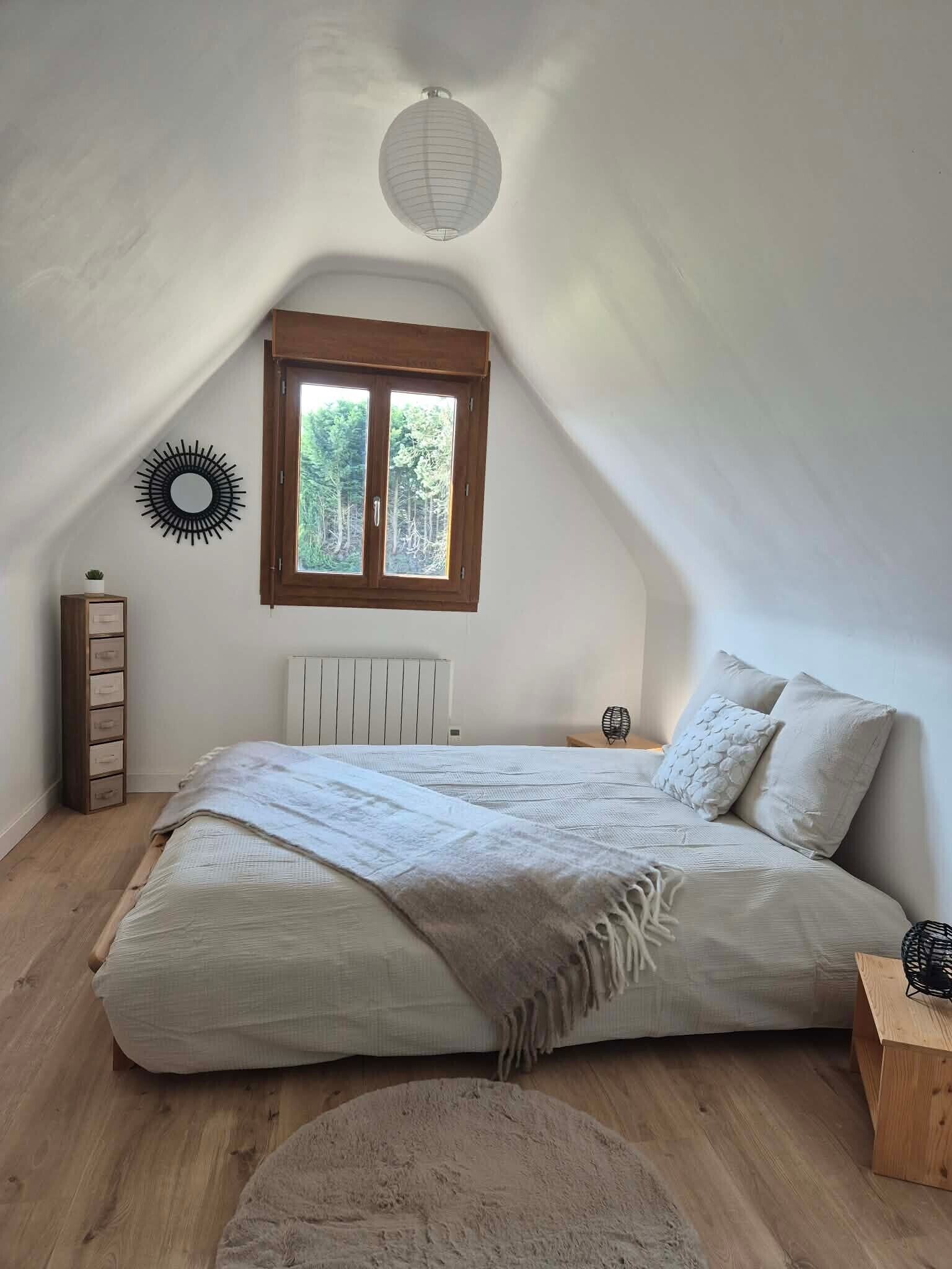 Ein Schlafzimmer mit einem Bett, einem Fenster, einer Heizung, einem Holzschrank und Wanddekoration.