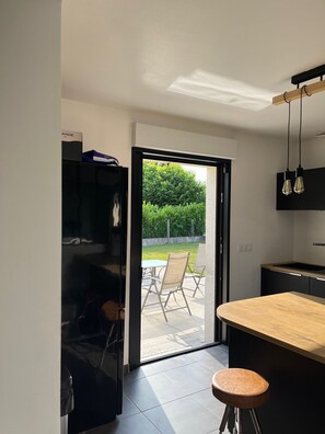 Une cuisine moderne dotée d’une porte-fenêtre coulissante donnant sur un patio extérieur.