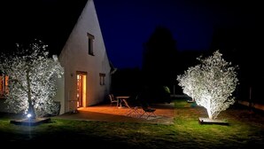A house with a triangular roof, a door, and a small patio with chairs. - Villa "Quiet House near Dinan" with Private Terrace, Garden, and Wi-Fi (Aucaleuc)