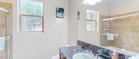 Un baño con un lavamanos blanco, un espejo grande y una ventana.