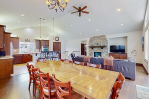 Un salón amplio con una gran mesa de comedor de madera, una chimenea de piedra y un televisor.