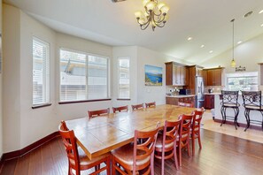 A spacious dining area with a large wooden table and chairs, a kitchen in the background, and a chandelier. - New Home in Coveted Location with Backyard - 10 Minutes to Ski Slopes, Beach (South Lake Tahoe)