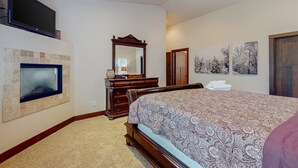 Une chambre dotée d’une télévision, d’une cheminée, d’une commode en bois, d’un lit et d’œuvres d’art.