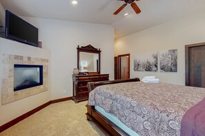 A bedroom with a TV, fireplace, wooden dresser, bed, and artwork. - New Home in Coveted Location with Backyard - 10 Minutes to Ski Slopes, Beach (South Lake Tahoe)