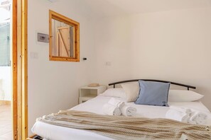 Ein Schlafzimmer mit Bett, Kissen, Nachttisch, Spiegel und Fenster.