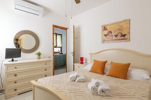 Ein Schlafzimmer mit Bett, Kommode, Spiegel, Klimaanlage und einem Bild an der Wand.