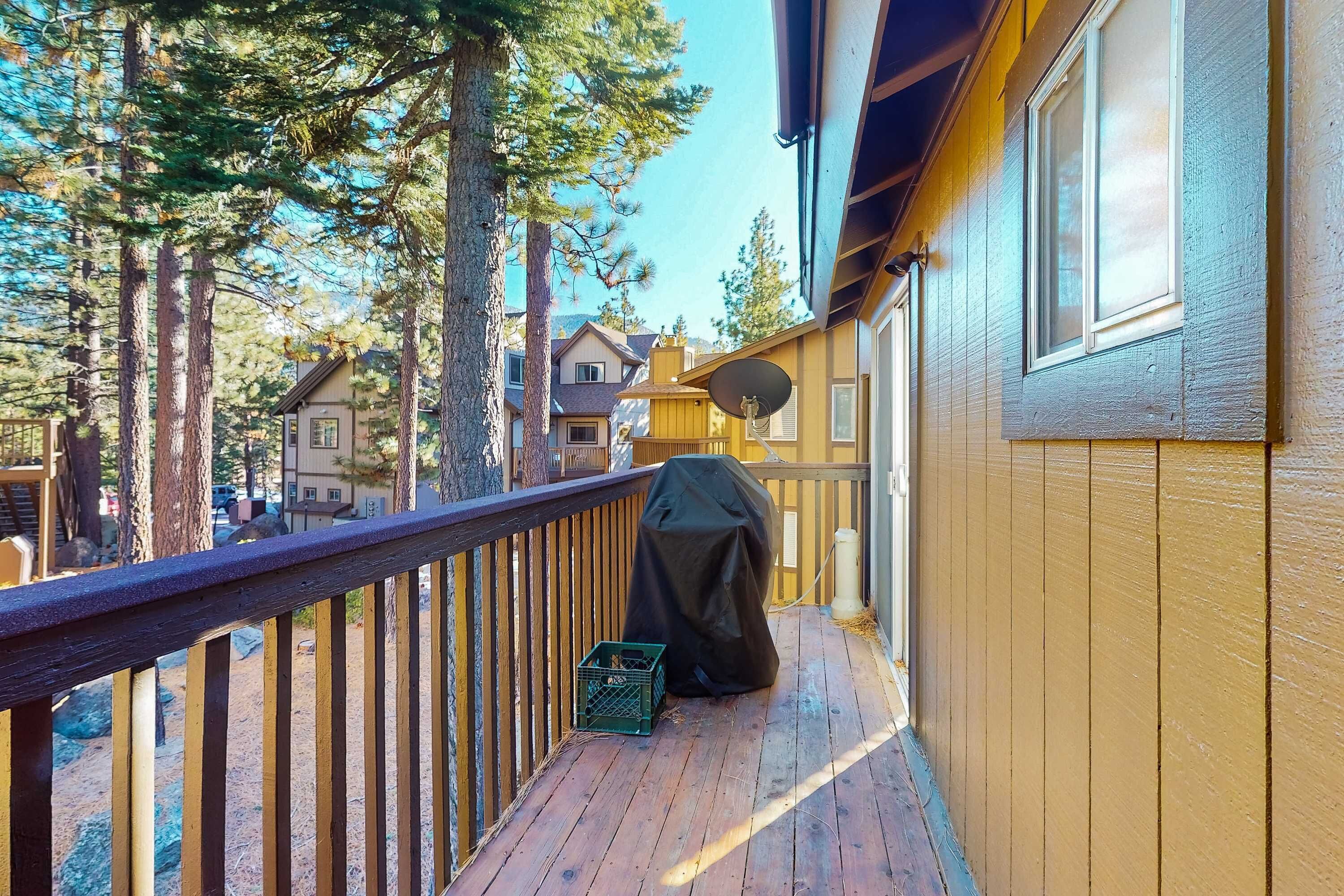 A wooden deck with a railing, a covered grill, and a satellite dish.