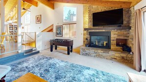 A cozy living room with a foosball table, a fireplace, and a television. - Townhome with pool, sauna, tennis, private hot tub, & foosball, sleeps 8 (Zephyr Cove)
