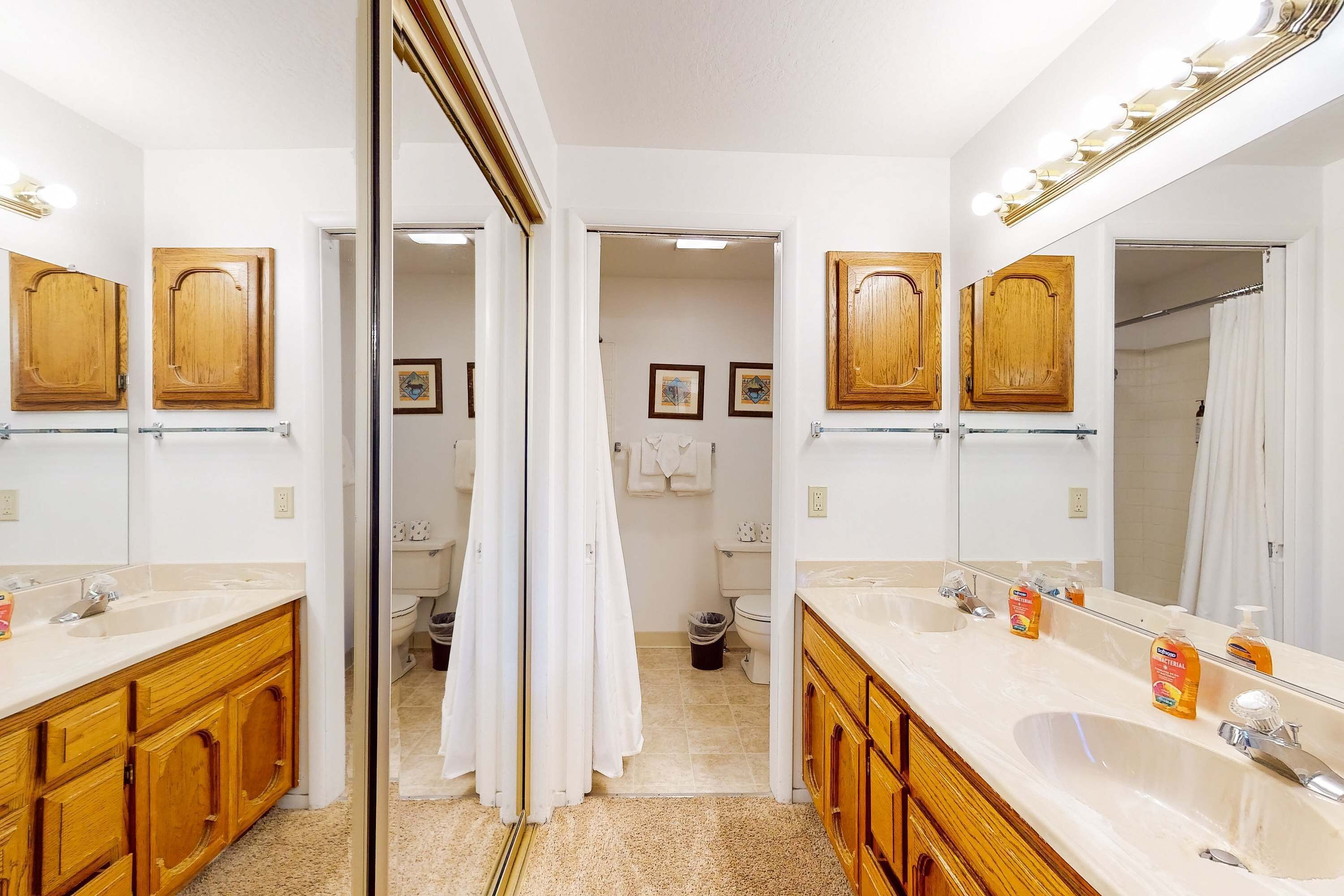 A bathroom with two sinks, wooden cabinets, a large mirror, and a shower curtain.