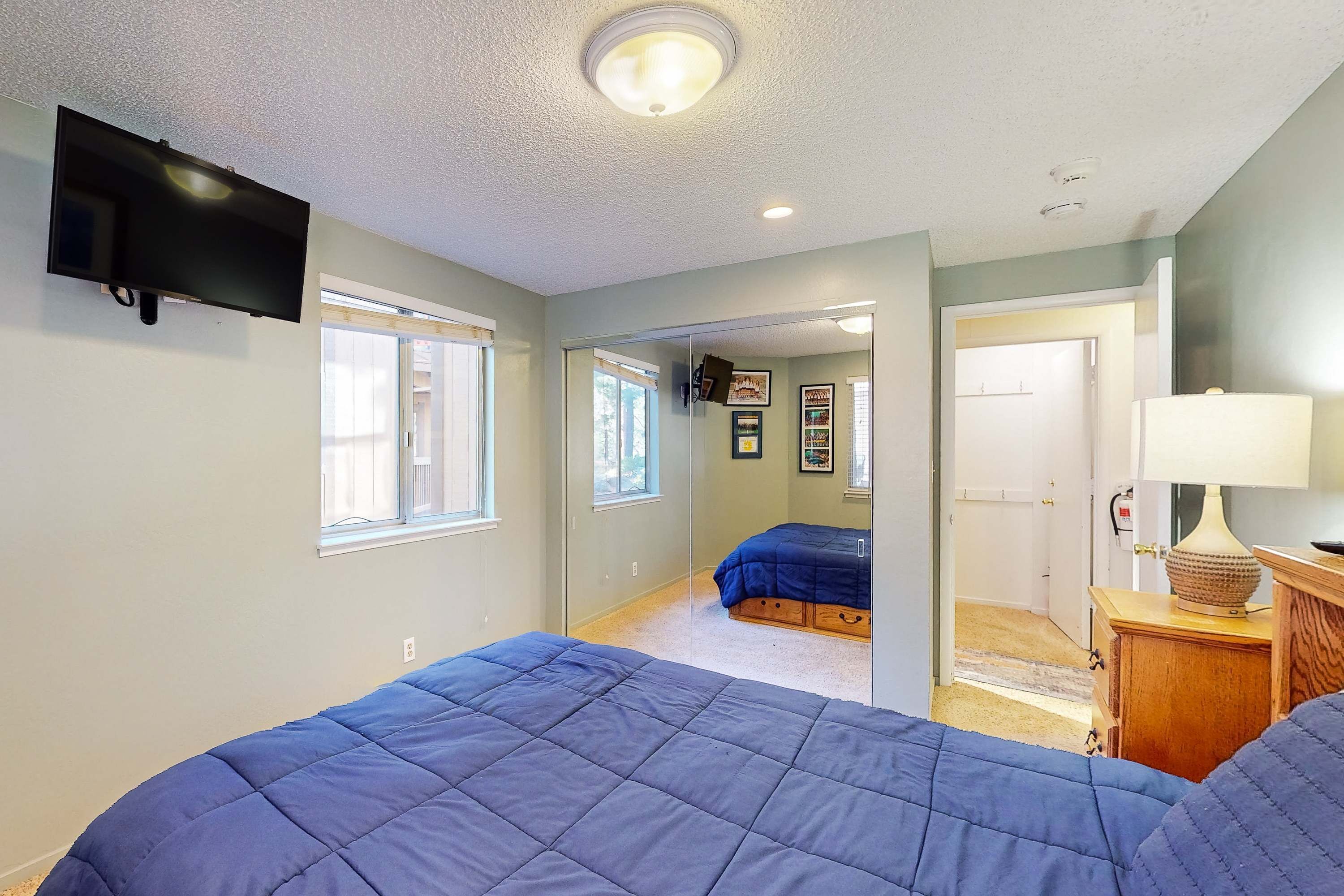 A bedroom with two beds, a TV, and a door leading to another room.