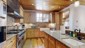 Una cocina con armarios de madera, encimera de granito, electrodomésticos de acero inoxidable y una ventana.