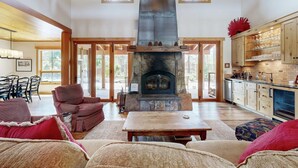 Un amplio salón con chimenea de piedra, muebles de madera y una cocina con armarios de madera.