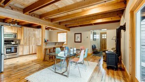 A spacious kitchen with wooden beams, a dining area with a glass table, and a wood-burning stove. - Home with private hot tub, 2 fireplaces, & W&D - drive minutes to hiking, golf (Truckee)