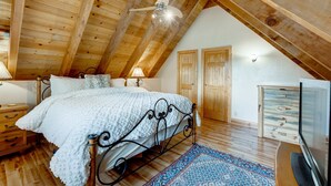 A bedroom with a wooden ceiling, a bed with a white blanket, a TV, and a wooden dresser. - Home with private hot tub, 2 fireplaces, & W&D - drive minutes to hiking, golf (Truckee)