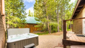 A hot tub with steps, a wooden deck, and a cabin in a forested area. - Home with private hot tub, 2 fireplaces, & W&D - drive minutes to hiking, golf (Truckee)