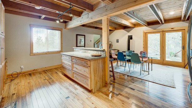 A spacious kitchen with wooden beams, a large island, and a dining area with chairs and a table. - Home with private hot tub, 2 fireplaces, & W&D - drive minutes to hiking, golf (Truckee)