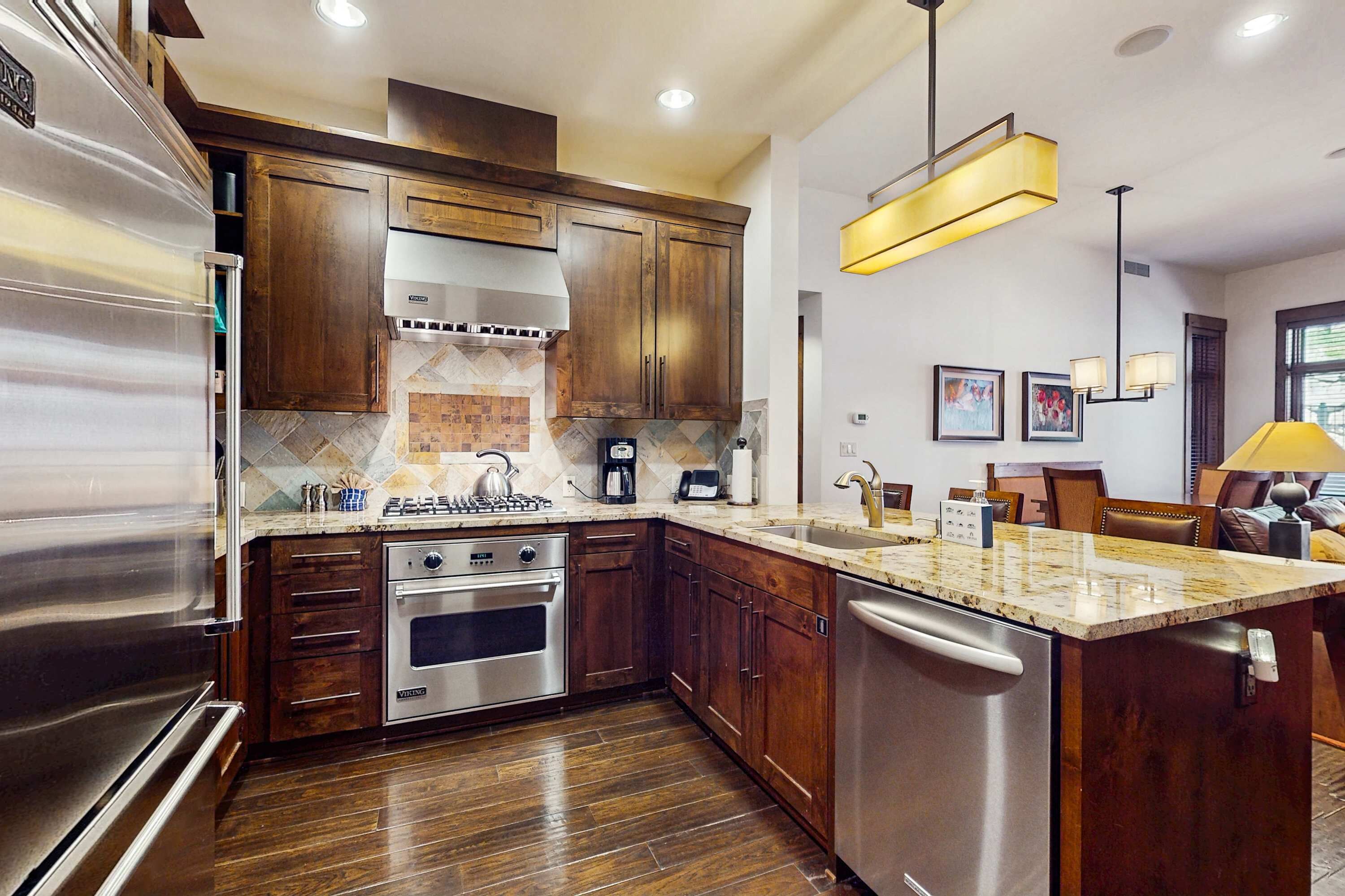 A modern kitchen with stainless steel appliances, wooden cabinets, and a marble countertop.