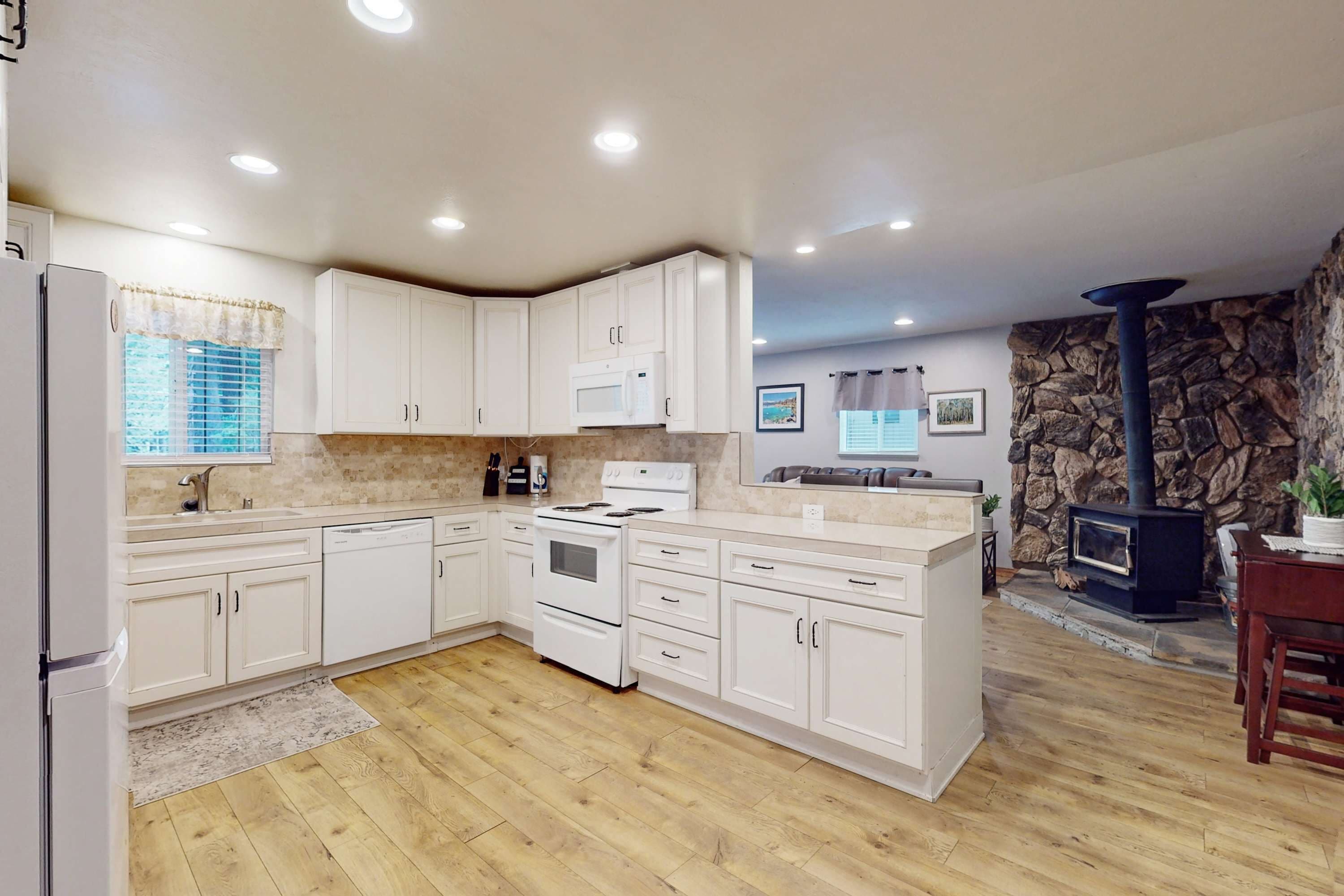 A modern kitchen with white cabinets, a stove, and a microwave.