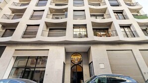 Un immeuble à plusieurs étages doté de balcons, une entrée principale avec une porte décorative et un portail de garage.