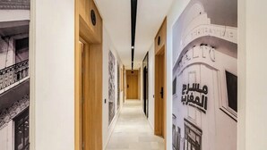 Un couloir avec des portes en bois, un sol à motifs et un mur orné d’un texte en arabe.