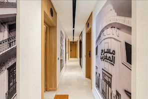 Ein Flur mit Holztüren, einem gemusterten Boden und einer Wand mit arabischer Schrift.