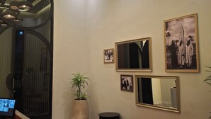 Un hall d’entrée avec un comptoir de réception, un banc, une plante en pot et des tableaux accrochés au mur.
