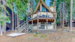 Eine Holzhütte mit einer Holztreppe, einem Balkon und Blick auf den umliegenden Wald.