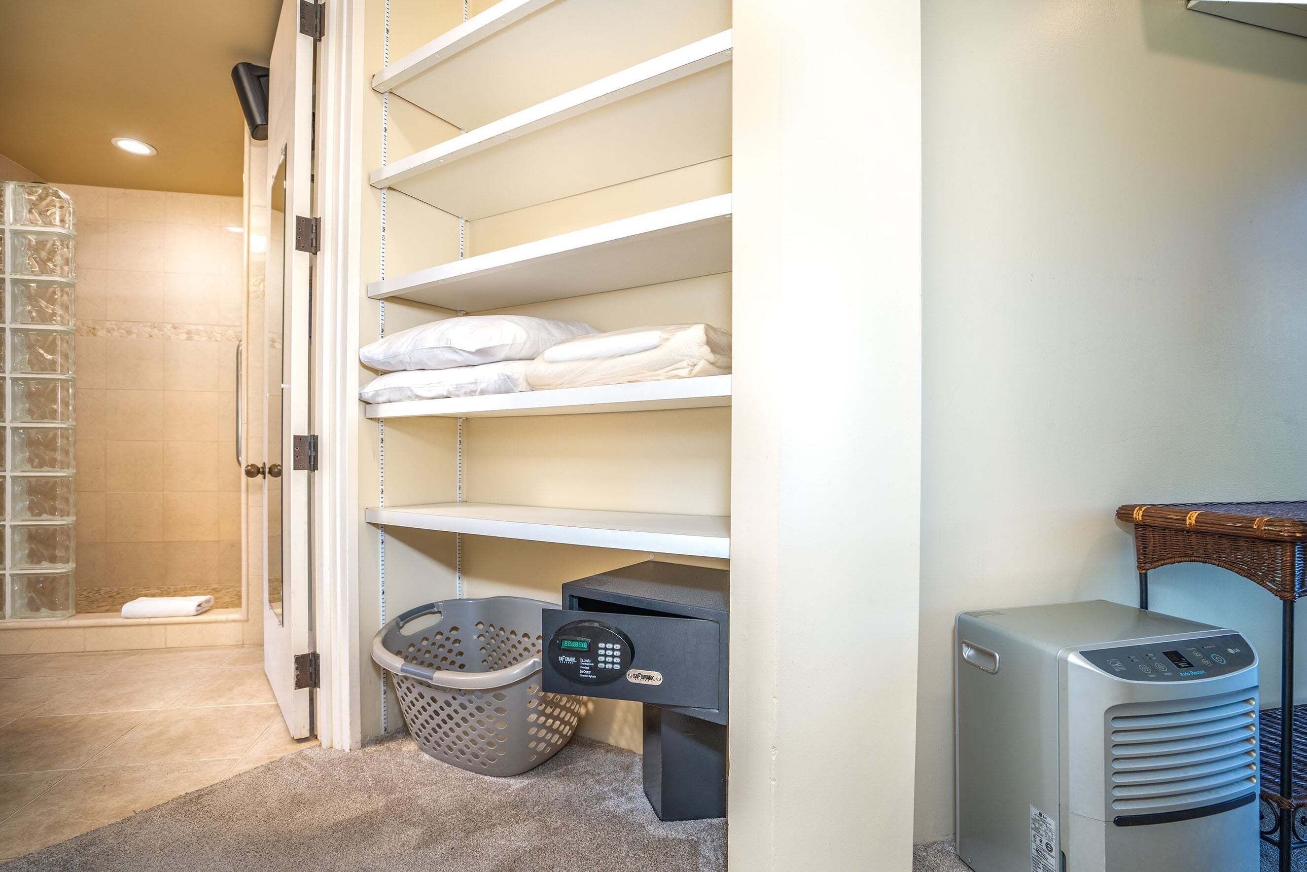 A bathroom with a shower, a towel rack, a laundry basket, and a heater.