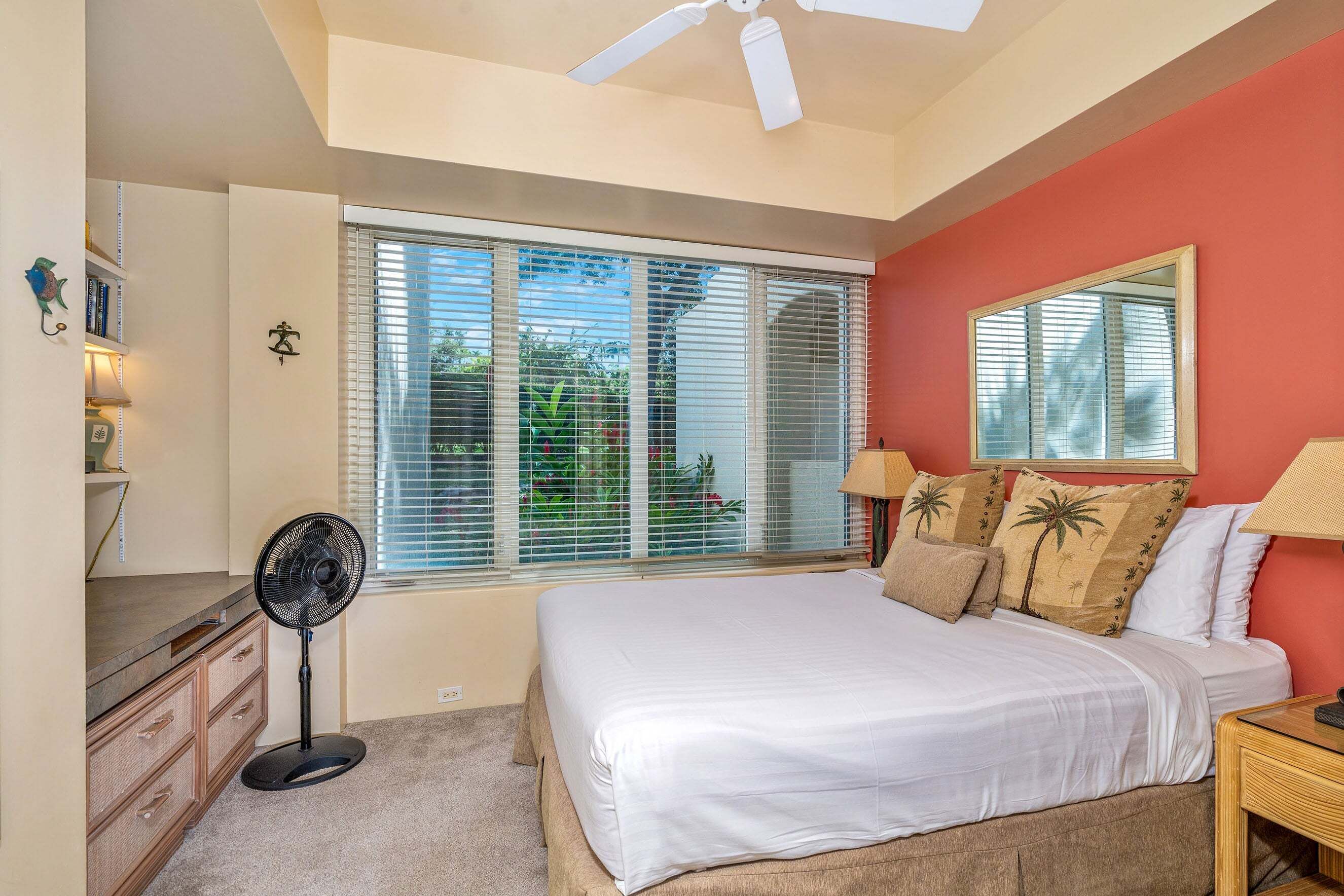 A bedroom with a bed, a standing fan, a window with blinds, a ceiling fan, and a nightstand.