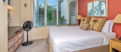 A bedroom with a bed, a standing fan, a window with blinds, a ceiling fan, and a nightstand.