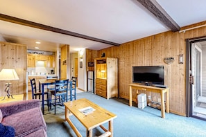 Ein Zimmer mit Holzvertäfelung, einem Essbereich, einem Fernseher und einem Sofa.