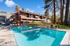 A swimming pool with lounge chairs, a wooden deck, and a multi-story building with balconies. - Find your perfect getaway to Lake Tahoe and Heavenly (South Lake Tahoe)
