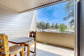 A balcony with a wooden table and chairs, a view of trees and houses, and a clear sky. - Find your perfect getaway to Lake Tahoe and Heavenly (South Lake Tahoe)