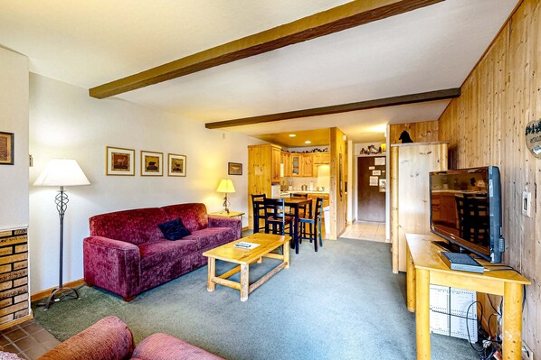 A cozy living room with a red sofa, a wooden coffee table, and a TV on a wooden stand. - Find your perfect getaway to Lake Tahoe and Heavenly (South Lake Tahoe)