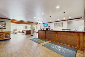 A reception area with a wooden reception desk, a television mounted on the wall, and a seating area with a sofa and chairs. - Explore Lake Tahoe living with skiing, hiking, boating, and more (South Lake Tahoe)