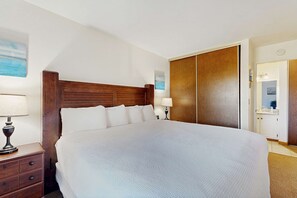 A bedroom with a large bed, wooden headboard, bedside tables with lamps, a wardrobe, and a painting on the wall. - Comfortable condo with pool, sauna, and hot tub access (South Lake Tahoe)