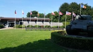 A building with a flagpole, a flag, and a statue. - B&B Hotel Bayeux (Bayeux)