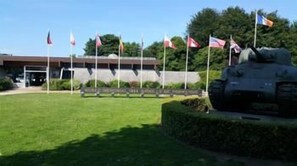 Un edificio con asta de bandera, una bandera y una estatua.