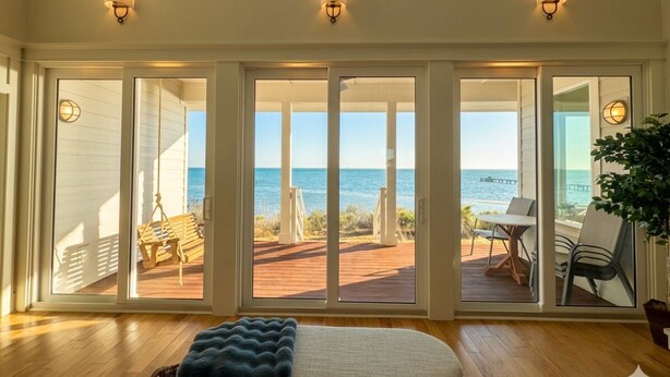 Ein Zimmer mit einer großen Schiebeglasdoor, die auf eine Terrasse mit Meerblick führt.