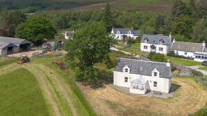 Et landligt landskab med et stort hvidt hus, en lade og en traktor.