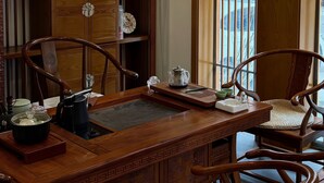 A traditional wooden desk with chairs, a window with a view, and a shelf with decorative items. - Your Lsle Inn (Zhangjiajie)